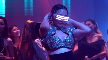 Bir grup insan disko gece kulübünde DJ 'in sahnede çaldığı müzikle dans ediyor.