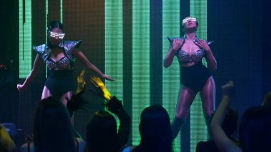 Bir grup insan disko gece kulübünde DJ 'in sahnede çaldığı müzikle dans ediyor.