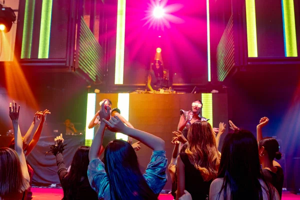 Grupo de personas bailan en discoteca al ritmo de la música de DJ en el escenario — Foto de Stock