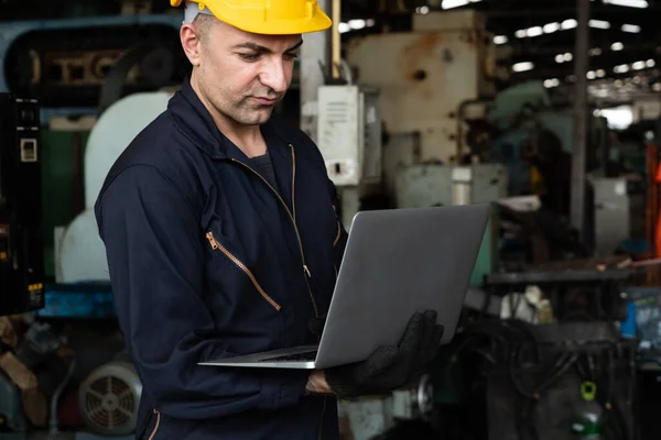 Trabajador hábil de la fábrica que trabaja con la computadora portátil para hacer la lista de verificación del procedimiento . — Foto de Stock