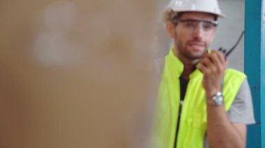 Profesyonel kargo işçisi başka bir işçiyle bağlantı kurmak için telsizle konuşuyor.