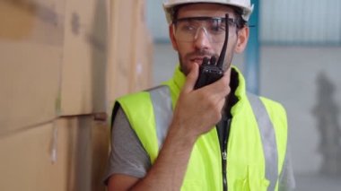 Profesyonel kargo işçisi başka bir işçiyle bağlantı kurmak için telsizle konuşuyor.