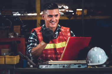 Fabrika işçisi, makine parçalarını incelerken taşınabilir radyodan konuşuyor.