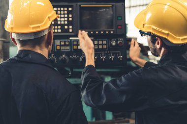 Bir grup yetenekli fabrika işçisi atölyede makine ekipmanı kullanıyor.