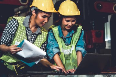 Fabrika işçileri fabrikada çalışıyor ve üretim planlarını tartışıyorlar.