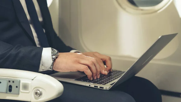 Молодий бізнесмен використовує ноутбук комп'ютера в літаку — стокове фото