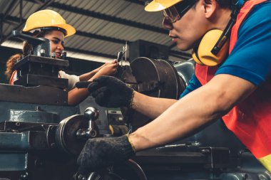 Bir grup yetenekli işçi fabrika atölyesinde makine teçhizatı kullanıyor.
