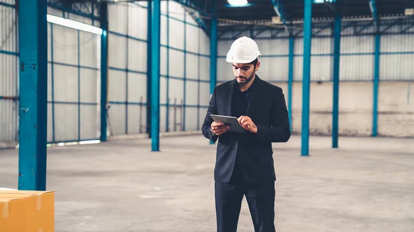 Factory manager using tablet computer in warehouse or factory