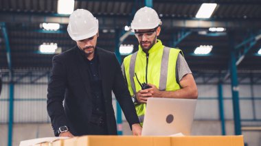 Fabrikada çalışan ve üretim planını tartışan iki fabrika işçisi. .