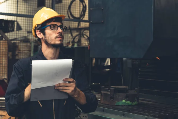 Умілий заводський працівник, який працює з кишені, щоб виконати контрольний список процедур роботи  . — стокове фото