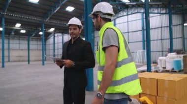 Fabrika işçileri depodaki bir yük arabasında kutu teslimatı yapıyor. .