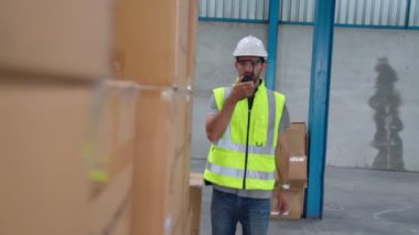 Profesyonel kargo işçisi başka bir işçiyle bağlantı kurmak için telsizle konuşuyor.