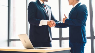Şirket ofisinde iş adamları el sıkışır.
