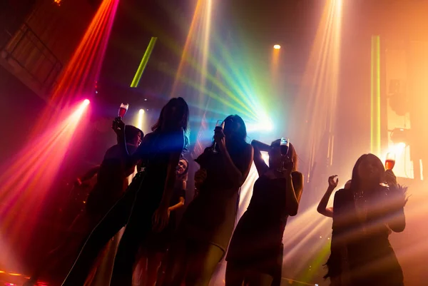 Silhouette image of people dance in disco night club to music from DJ on stage — Stock Photo, Image