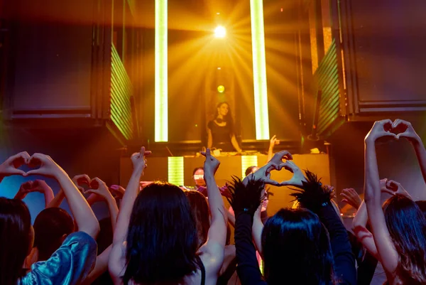 Grupo de personas bailan en discoteca al ritmo de la música de DJ en el escenario —  Fotos de Stock