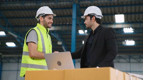 Two factory workers working and discussing manufacturing plan in the factory .