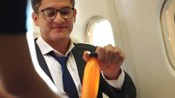 Empresário tem suco de laranja servido por uma aeromoça em avião — Fotografia de Stock