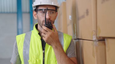 Profesyonel kargo işçisi başka bir işçiyle bağlantı kurmak için telsizle konuşuyor.