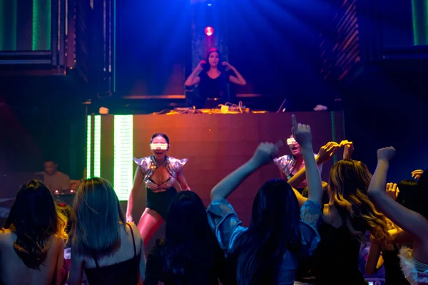 Grupo de personas bailan en discoteca al ritmo de la música de DJ en el escenario — Foto de Stock