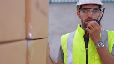 Profesyonel kargo işçisi başka bir işçiyle bağlantı kurmak için telsizle konuşuyor.