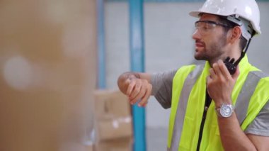 Profesyonel kargo işçisi başka bir işçiyle bağlantı kurmak için telsizle konuşuyor.