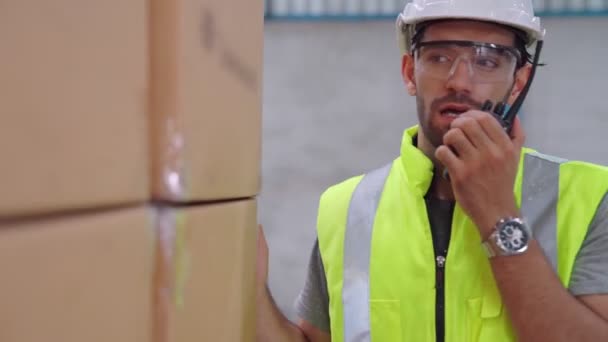 Professional cargo worker talks on portable radio to contact another worker — Stock Video