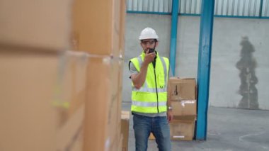 Profesyonel kargo işçisi başka bir işçiyle bağlantı kurmak için telsizle konuşuyor.