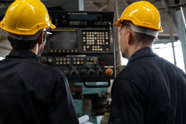 Bir grup yetenekli fabrika işçisi atölyede makine ekipmanı kullanıyor.