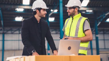 Fabrikada çalışan ve üretim planını tartışan iki fabrika işçisi. .
