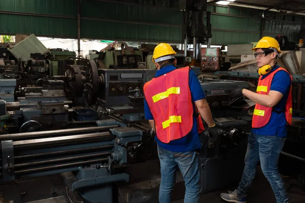 Group of skillful factory workers using machine equipment in workshop