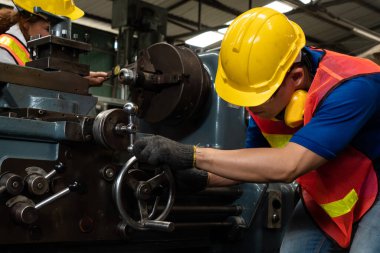 Bir grup yetenekli işçi fabrika atölyesinde makine teçhizatı kullanıyor.