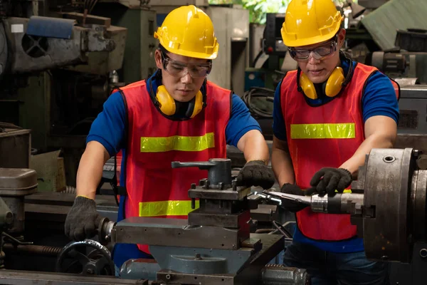 Group of skillful factory workers using machine equipment in workshop