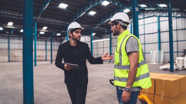 Fabrika işçileri depodaki bir yük arabasında kutu teslimatı yapıyor. .