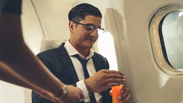 Бізнесмен має апельсиновий сік, який подає повітряна господиня в літаку — стокове фото