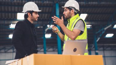 Fabrikada çalışan ve üretim planını tartışan iki fabrika işçisi. .