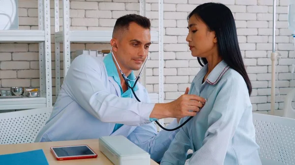 Doutor em uniforme profissional examinando paciente no hospital — Fotografia de Stock