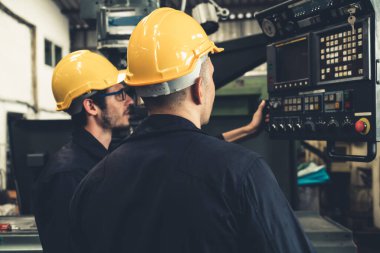 Bir grup yetenekli fabrika işçisi atölyede makine ekipmanı kullanıyor.