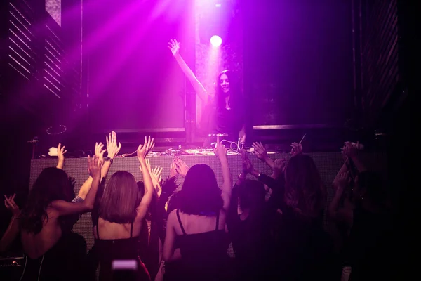 Grupo de personas bailan en discoteca al ritmo de la música de DJ en el escenario —  Fotos de Stock