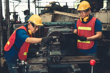 Bir grup yetenekli fabrika işçisi atölyede makine ekipmanı kullanıyor.