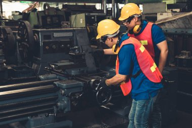 Bir grup yetenekli fabrika işçisi atölyede makine ekipmanı kullanıyor.