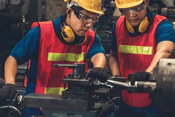 Groep bekwame fabrieksarbeiders die machineapparatuur gebruiken in de werkplaats — Stockfoto