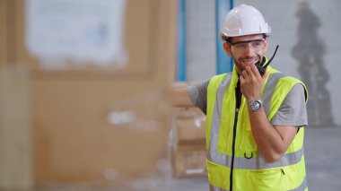 Profesyonel kargo işçisi başka bir işçiyle bağlantı kurmak için telsizle konuşuyor.
