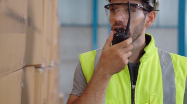 Profesyonel kargo işçisi başka bir işçiyle bağlantı kurmak için telsizle konuşuyor.