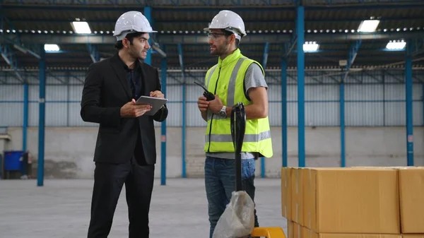 Two factory workers working and discussing manufacturing plan in the factory .