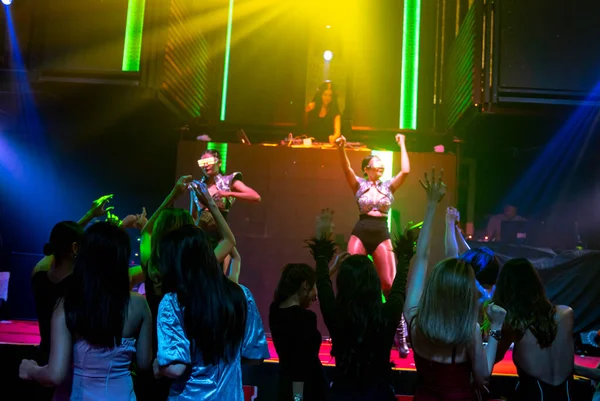 Grupo de personas bailan en discoteca al ritmo de la música de DJ en el escenario — Foto de Stock