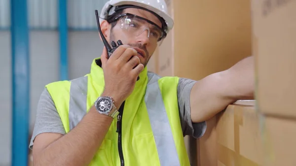 Professional cargo worker talks on portable radio to contact another worker — Stock Photo, Image