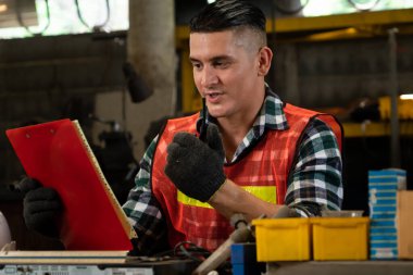 Fabrika işçisi, makine parçalarını incelerken taşınabilir radyodan konuşuyor.