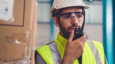 Profesyonel kargo işçisi başka bir işçiyle bağlantı kurmak için telsizle konuşuyor.