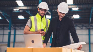 Fabrikada çalışan ve üretim planını tartışan iki fabrika işçisi. .