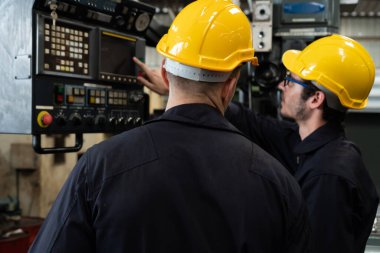 Bir grup yetenekli fabrika işçisi atölyede makine ekipmanı kullanıyor.